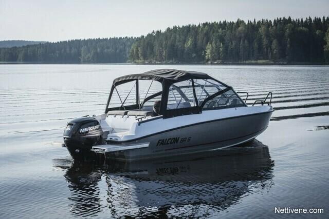 A white Falcon 56 boat with a black canopy is anchored on calm waters, surrounded by forested shoreline.